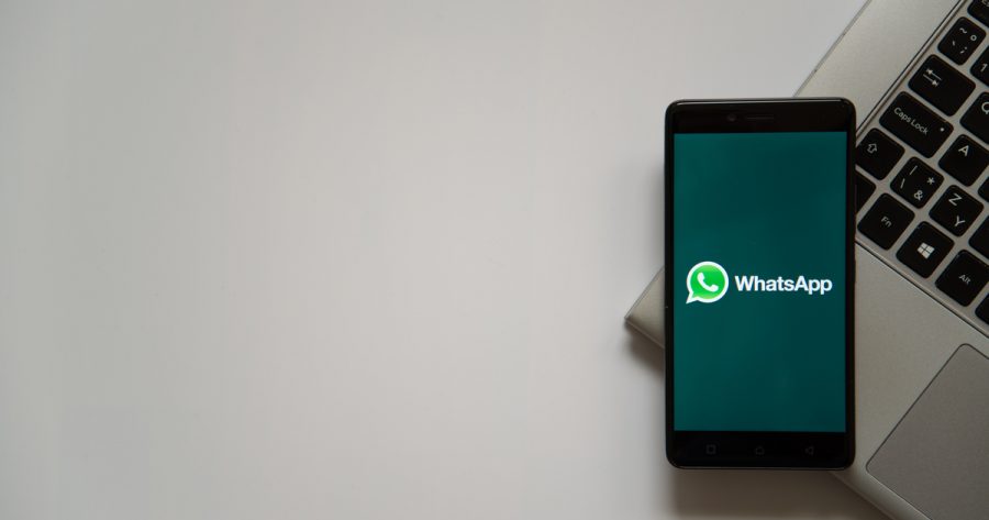 Whatsapp logo on smartphone screen placed on laptop keyboard